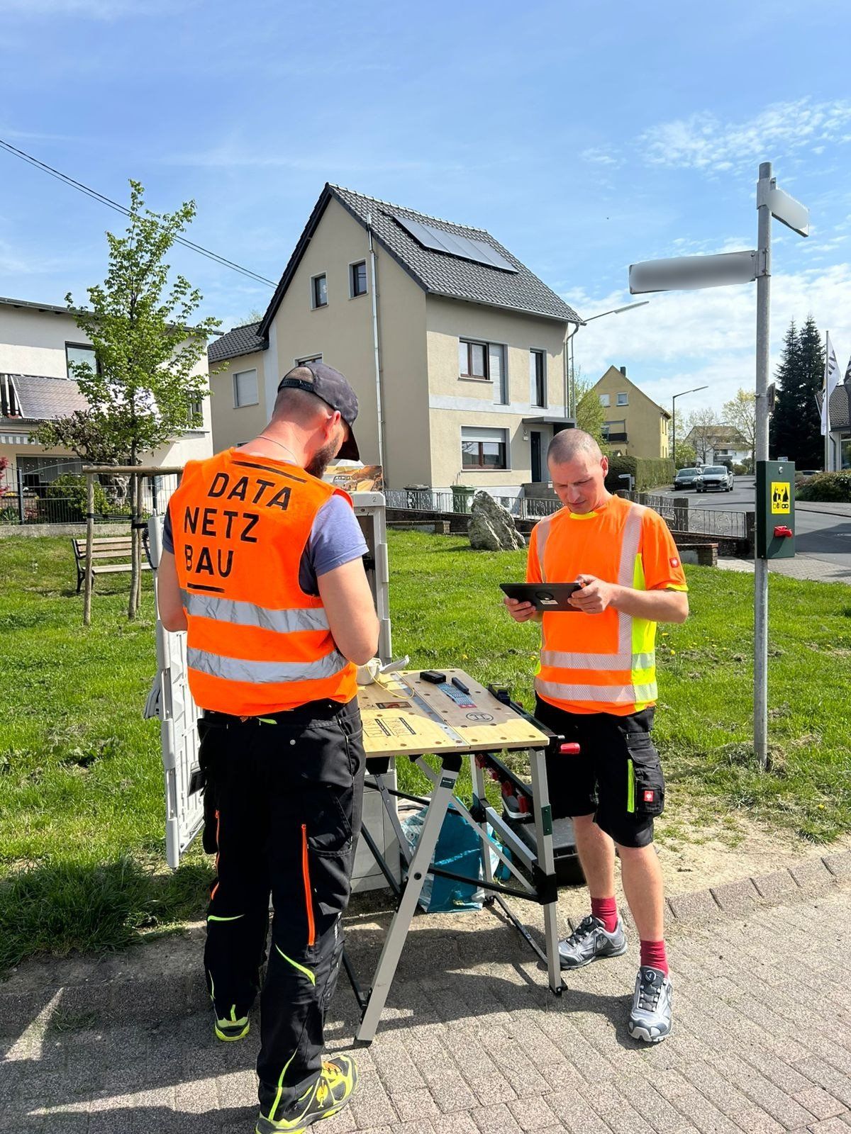 DataNetzBau Techniker bei Glasfaser-Installationsarbeiten vor einem Wohnhaus